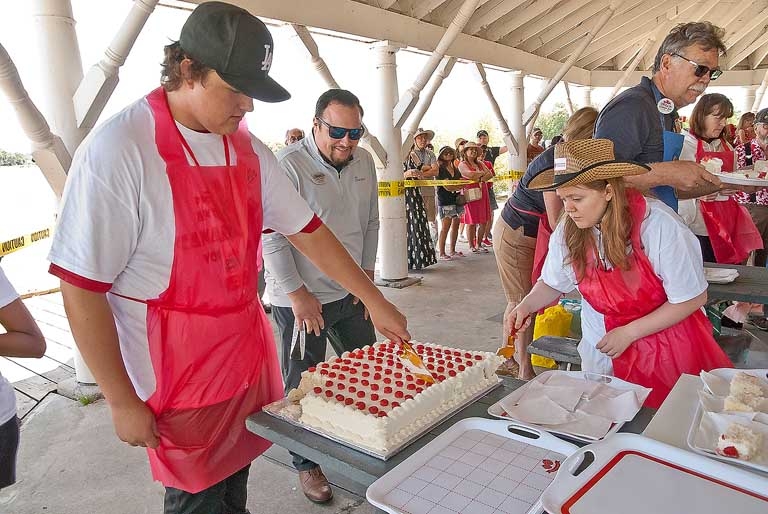 2024 Canada Day volunteers Logan Scott and Sydnei Gaudet preparing the Canada Day cake for it's disappering act.