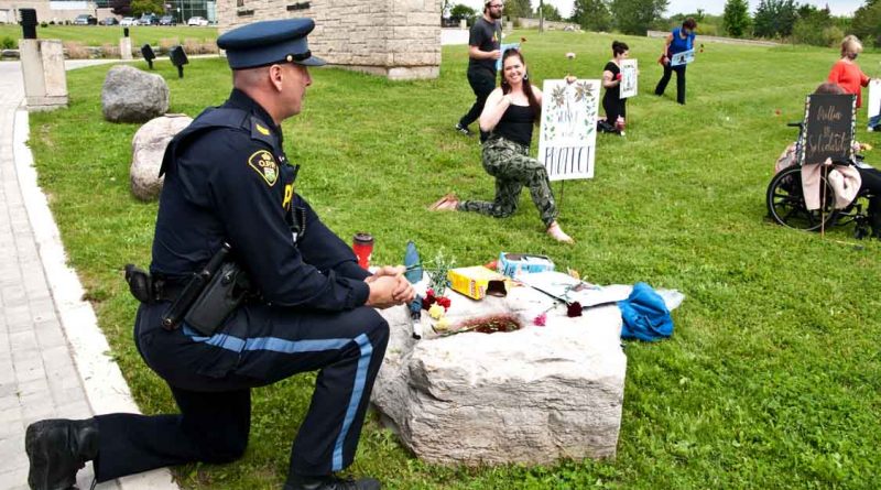OPP Sgt. Kerry Schmidt joins protesters taking a knee. at Wednesday's protest.